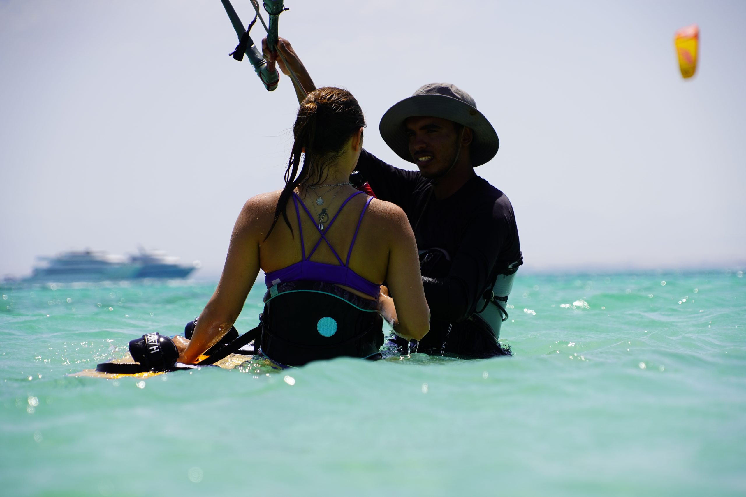 group of 5 girls sitting on the kite beach in El Gouna in Egypt, looking at the kites in the water. The image shows the girls from the back, all wearing a Kite Tribe T-Shirt