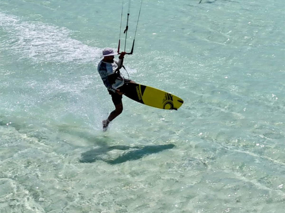 group of 5 girls sitting on the kite beach in El Gouna in Egypt, looking at the kites in the water. The image shows the girls from the back, all wearing a Kite Tribe T-Shirt
